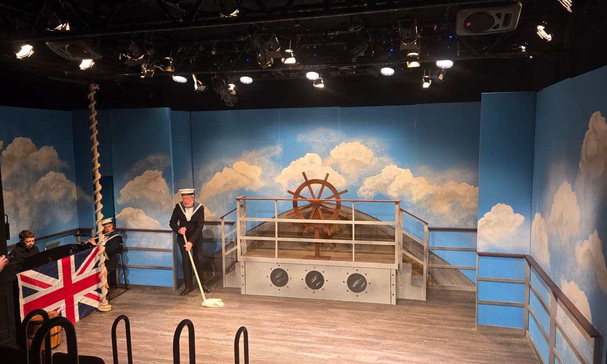 Image of a stage with a ship set and sailor mopping the floor