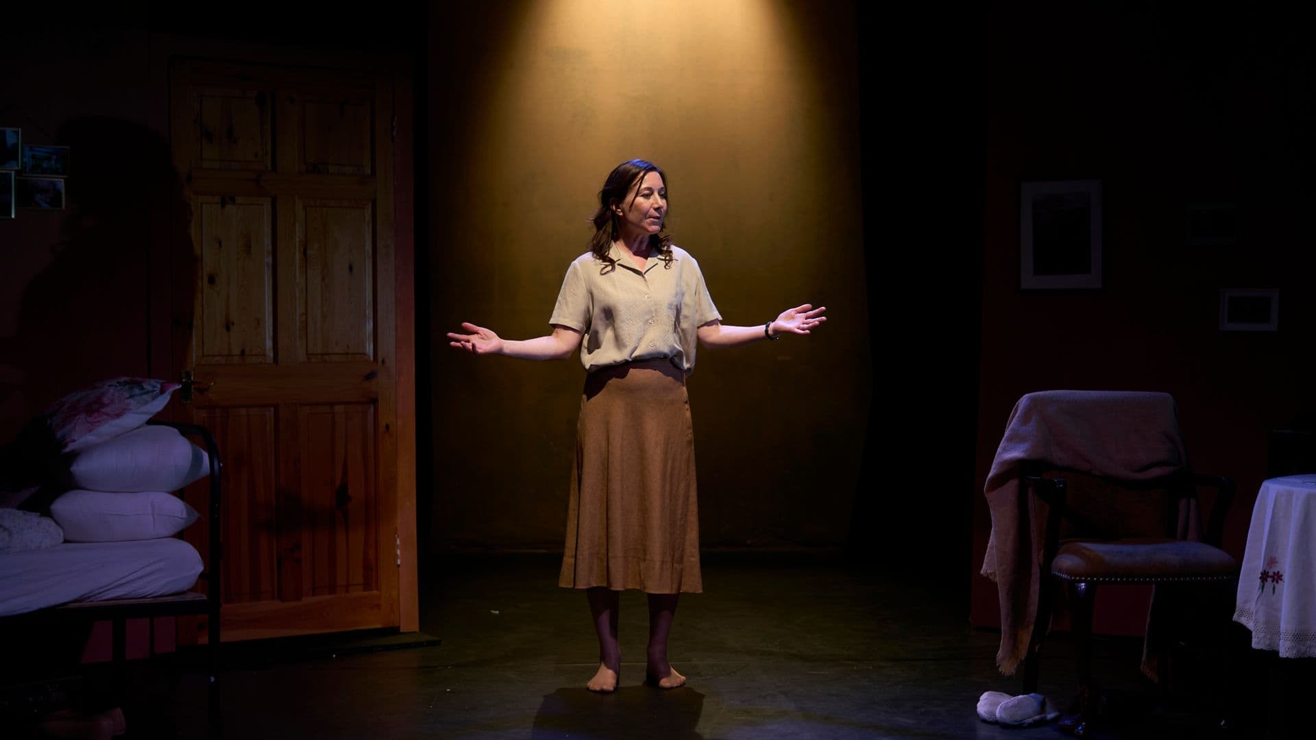 A woman centre stage in spotlight with arms wide